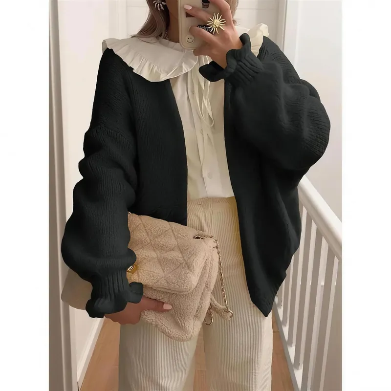 The cardigan in black, worn indoors over a blouse