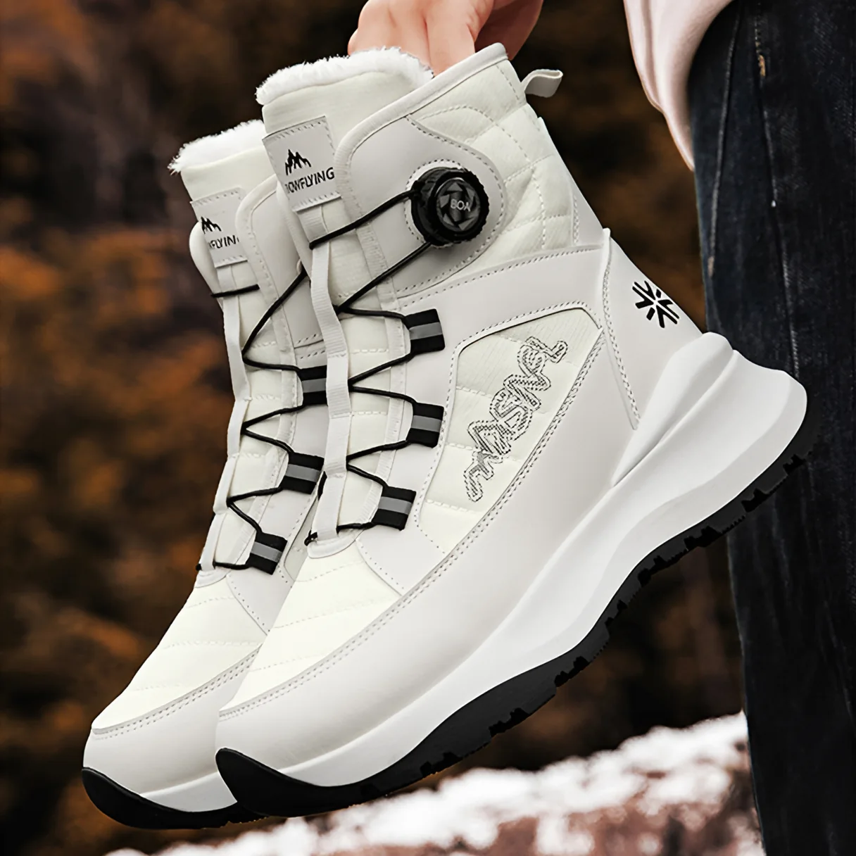 Hand holding a pair of White boots, showing the lacing knobs
