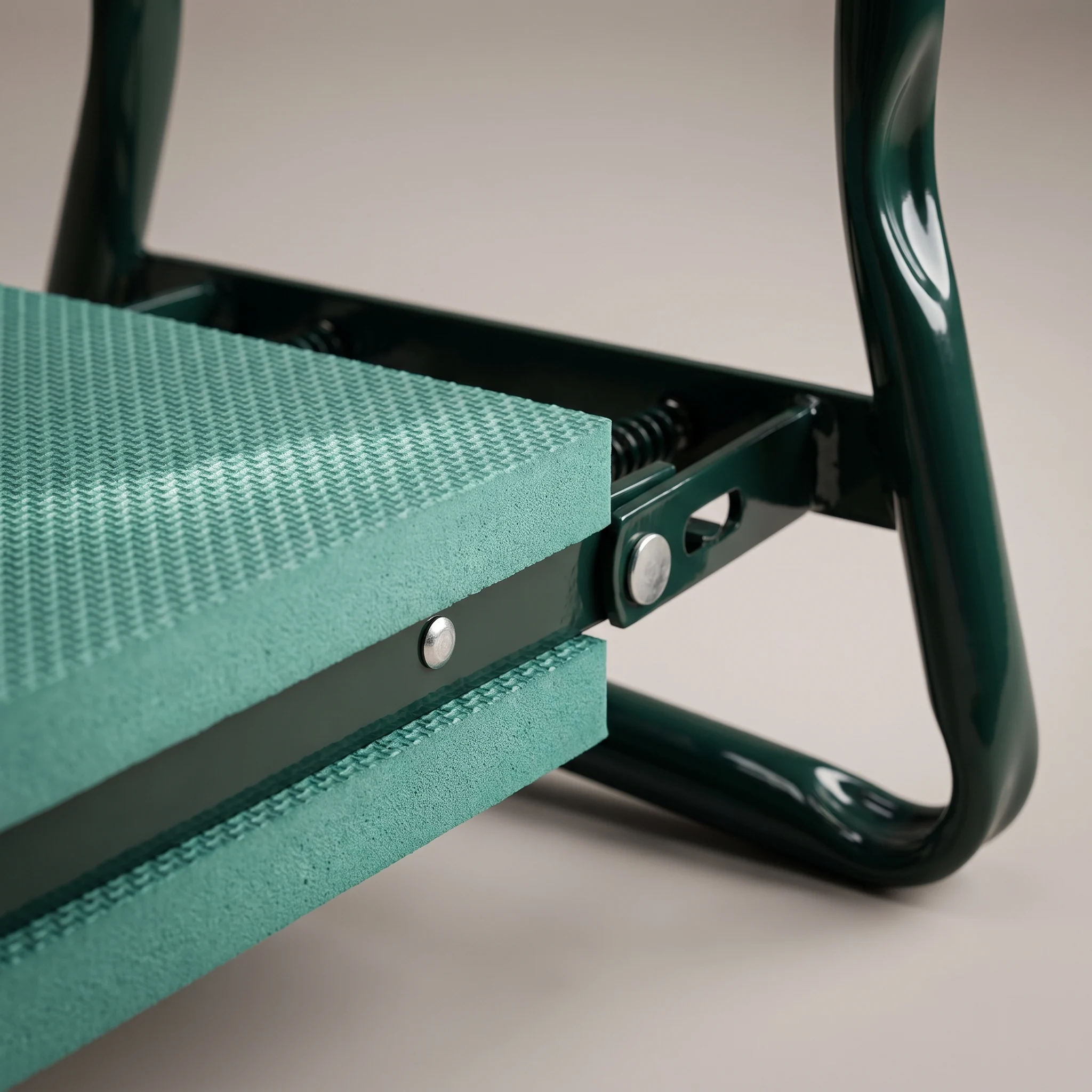 Close-up of the thick textured EVA foam pad riveted to the dark green powder-coated steel frame