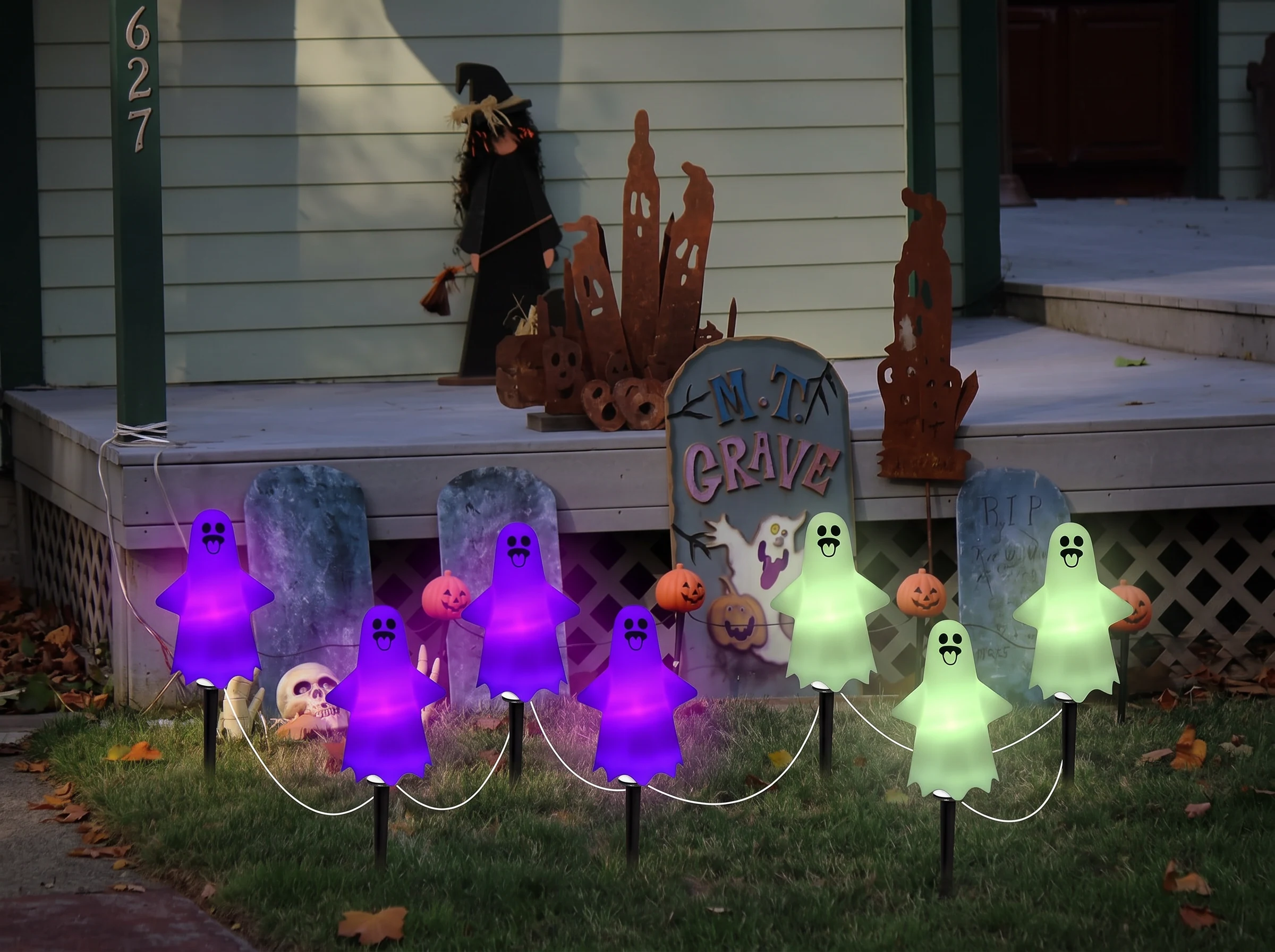 A run of solar ghost stake lights across a lawn at night, some glowing purple and some pale green as the colour cycle moves along the run