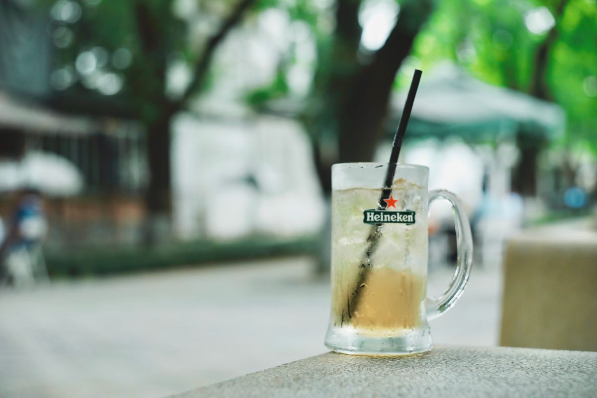Close-up of a Heineken beer mug with ice, blurred outdoor background, summer vibe.