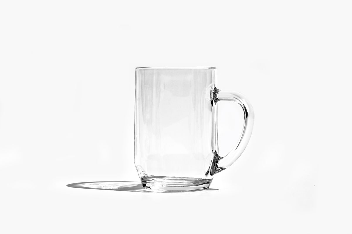 A clear glass mug casting a shadow against a clean white backdrop, showcasing simplicity and elegance.