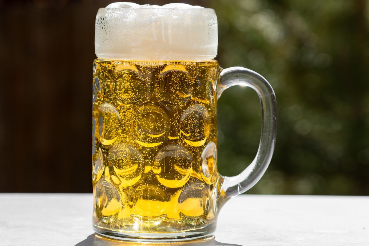 A refreshing glass of golden lager beer with frothy head, served outdoors in Munich, Germany.