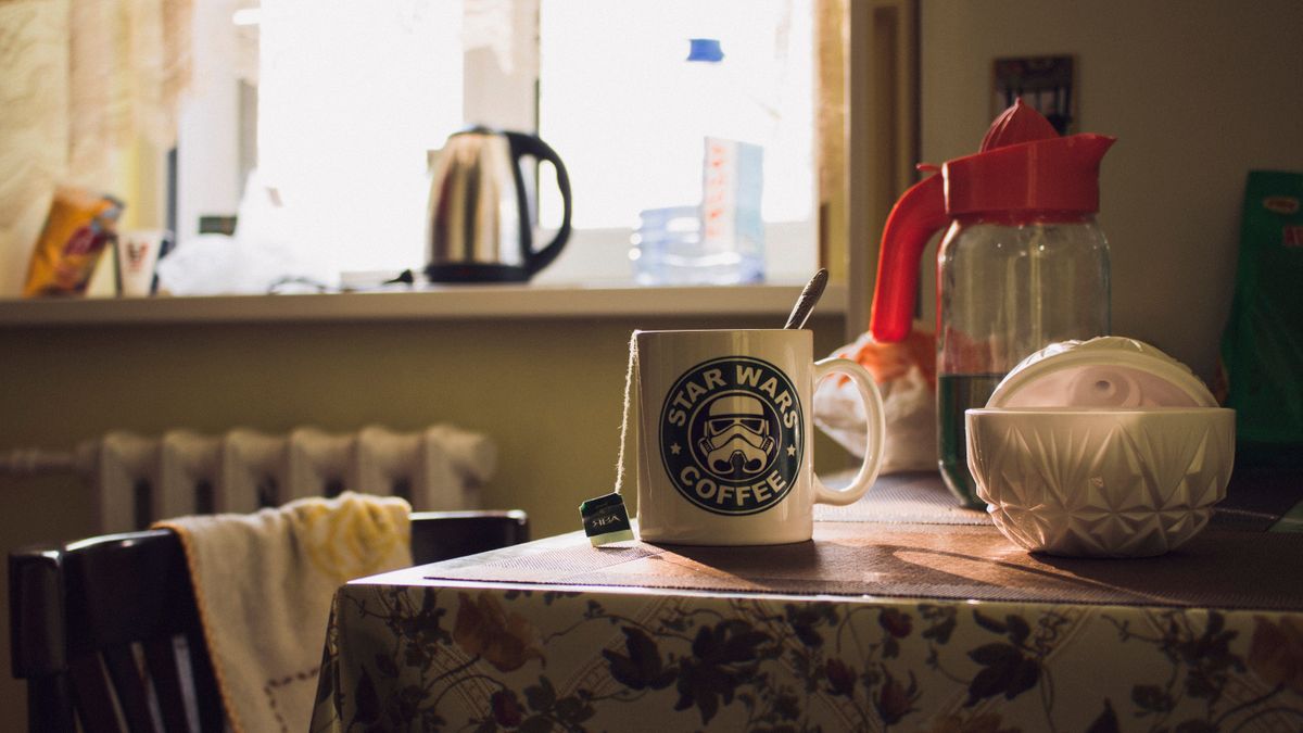A Star Wars-themed coffee mug on a kitchen table, with morning light streaming in.
