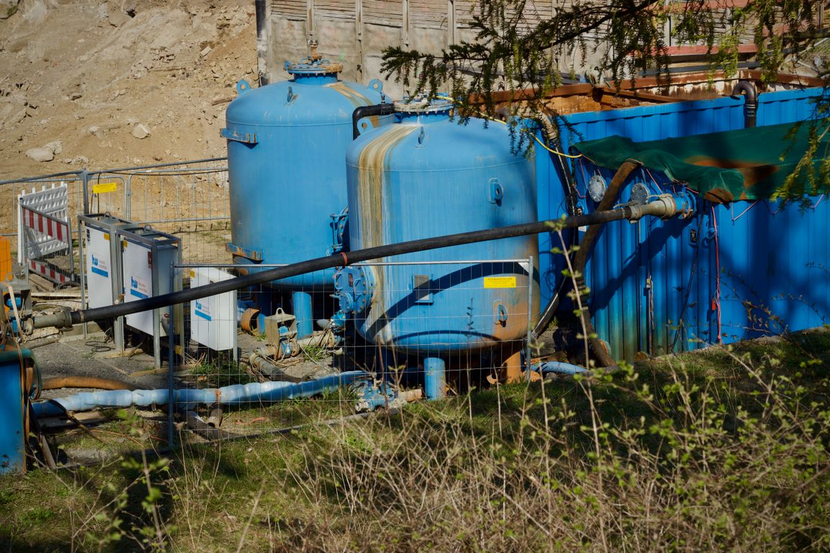 Outdoor industrial water filtration plant with large blue tanks under sunlight.