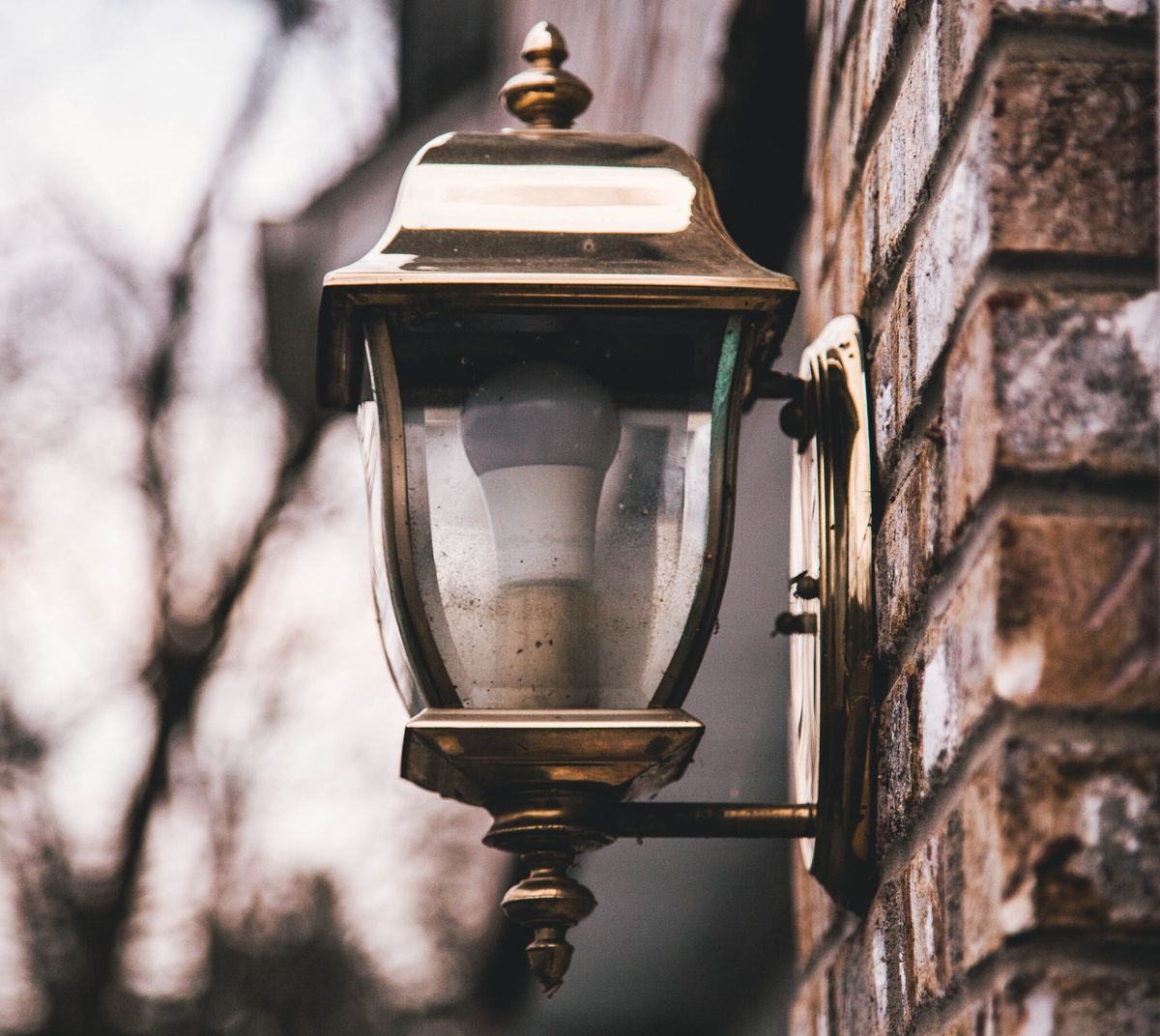 Close-up of a vintage outdoor lantern mounted on a brick wall, evoking a classic ambiance.