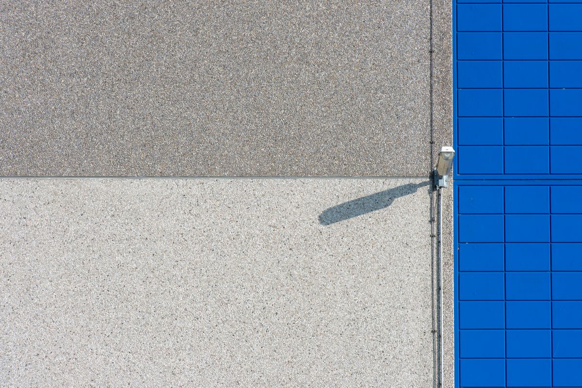 A modern building facade with solar panels and a security light, showcasing clean lines and textures.