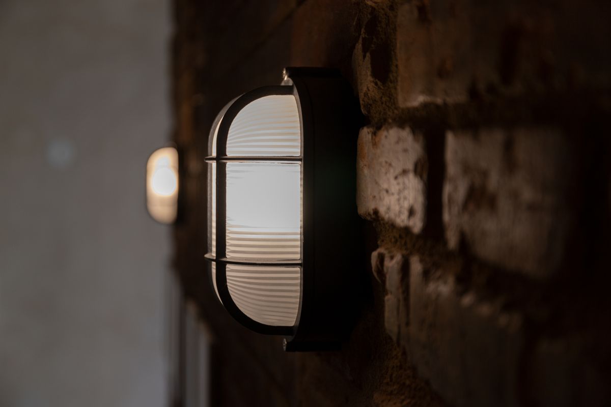 Close-up of a vintage industrial lamp on a brick wall with soft lighting.