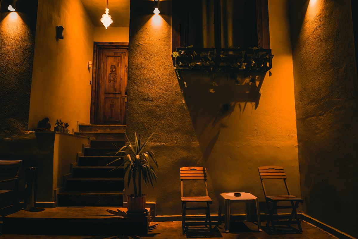 Warmly lit patio with chairs under dramatic lighting, creating a cozy atmosphere.
