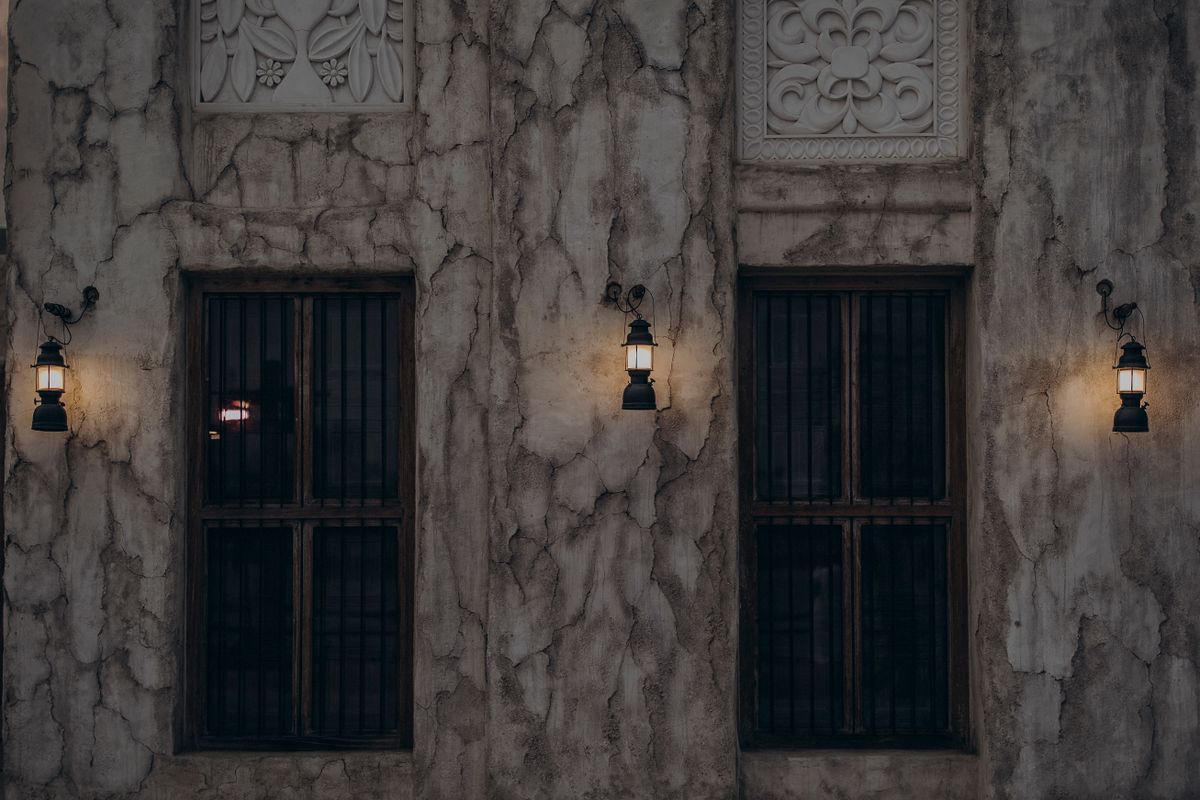 Vintage Dubai architecture featuring rustic windows and warm lantern lighting on a textured wall.