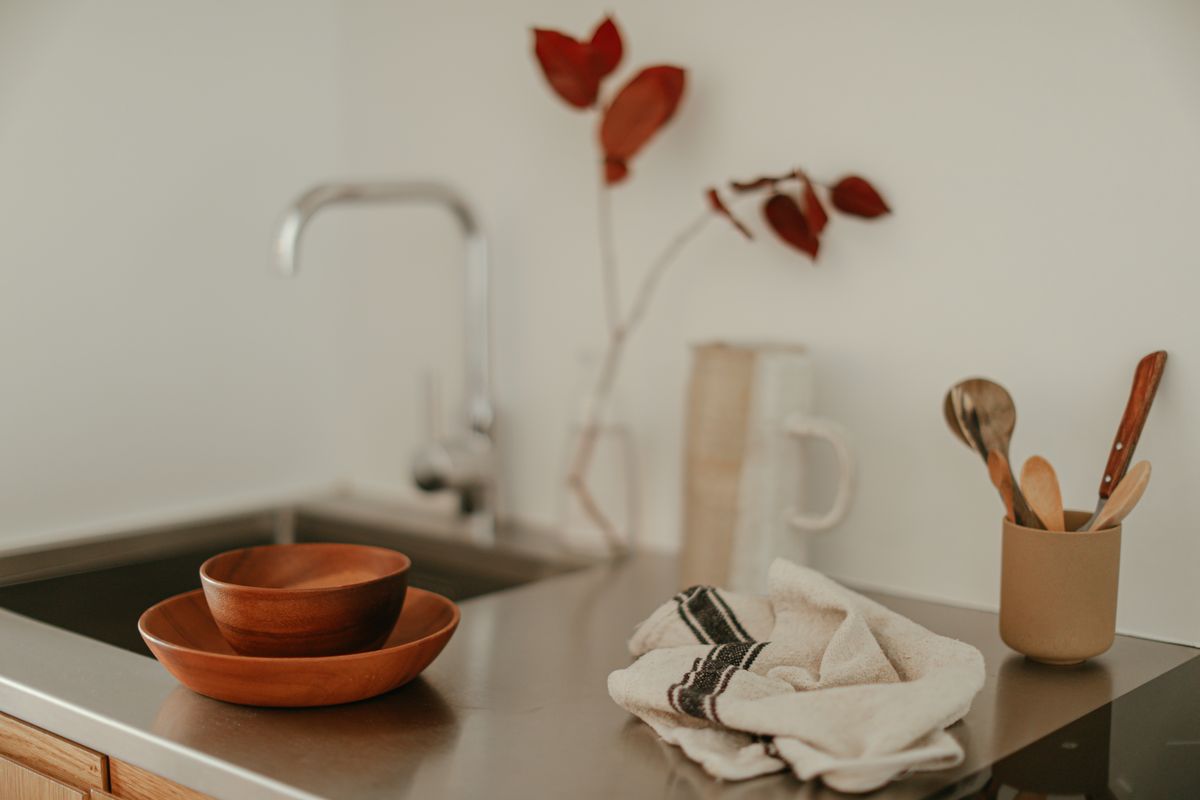 A modern kitchen sink with wooden utensils and a minimalist decor vibe.