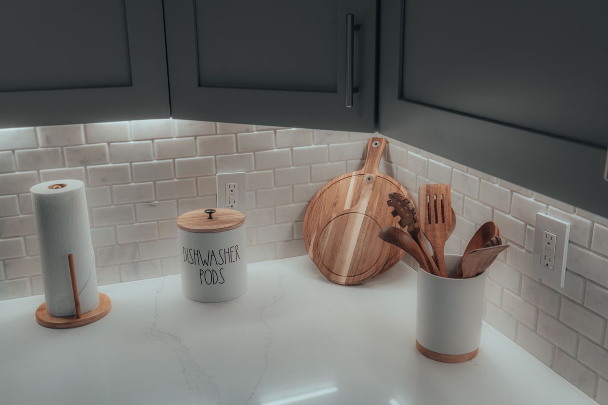 Clean and organized kitchen countertop featuring wooden utensils and stylish containers.