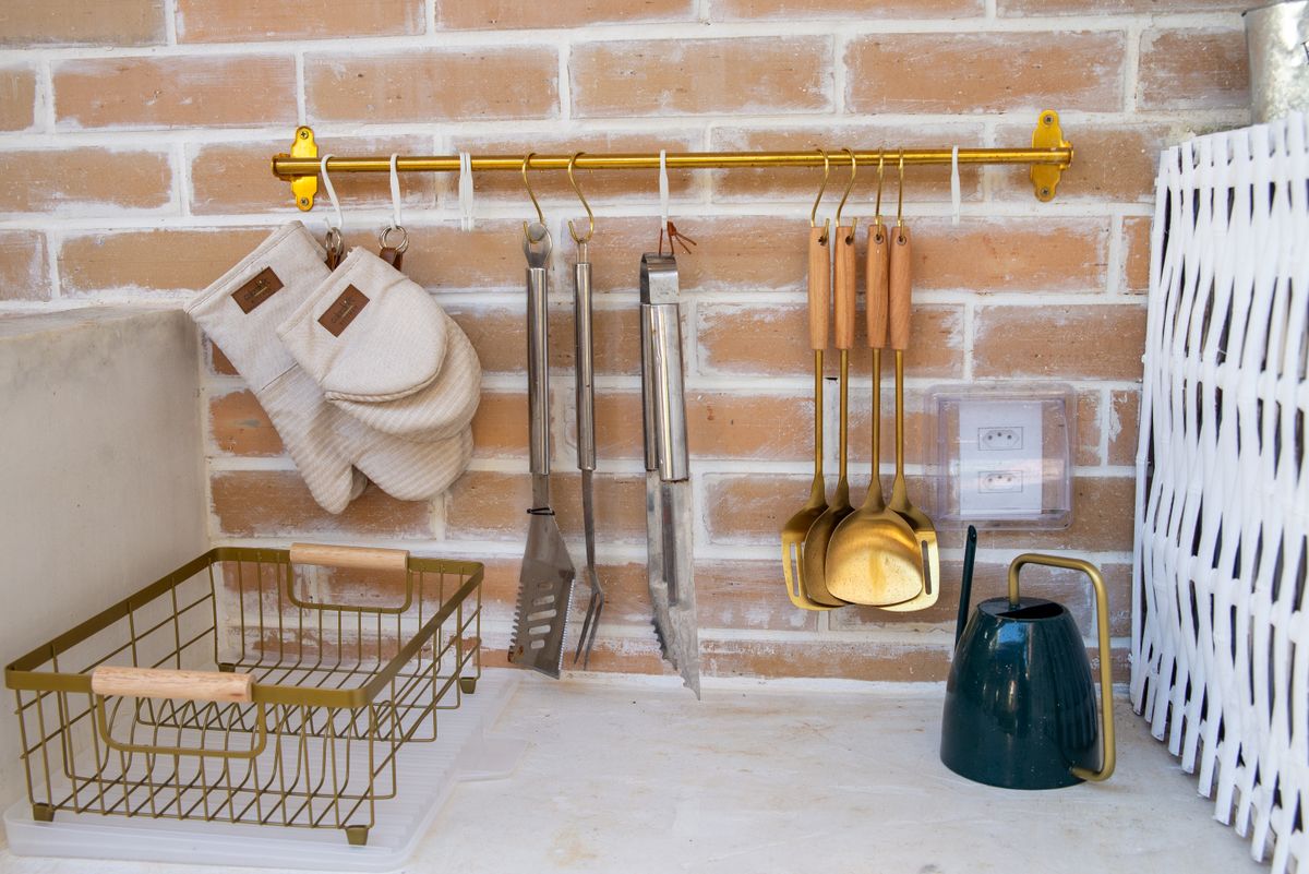 Elegant kitchen setup with utensils and accessories on a brick wall.