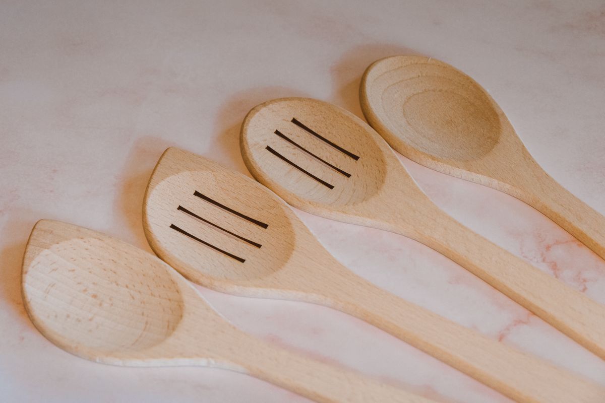 Close-up of wooden cooking spoons and spatulas arranged on a marble countertop. Ideal for kitchen decor.