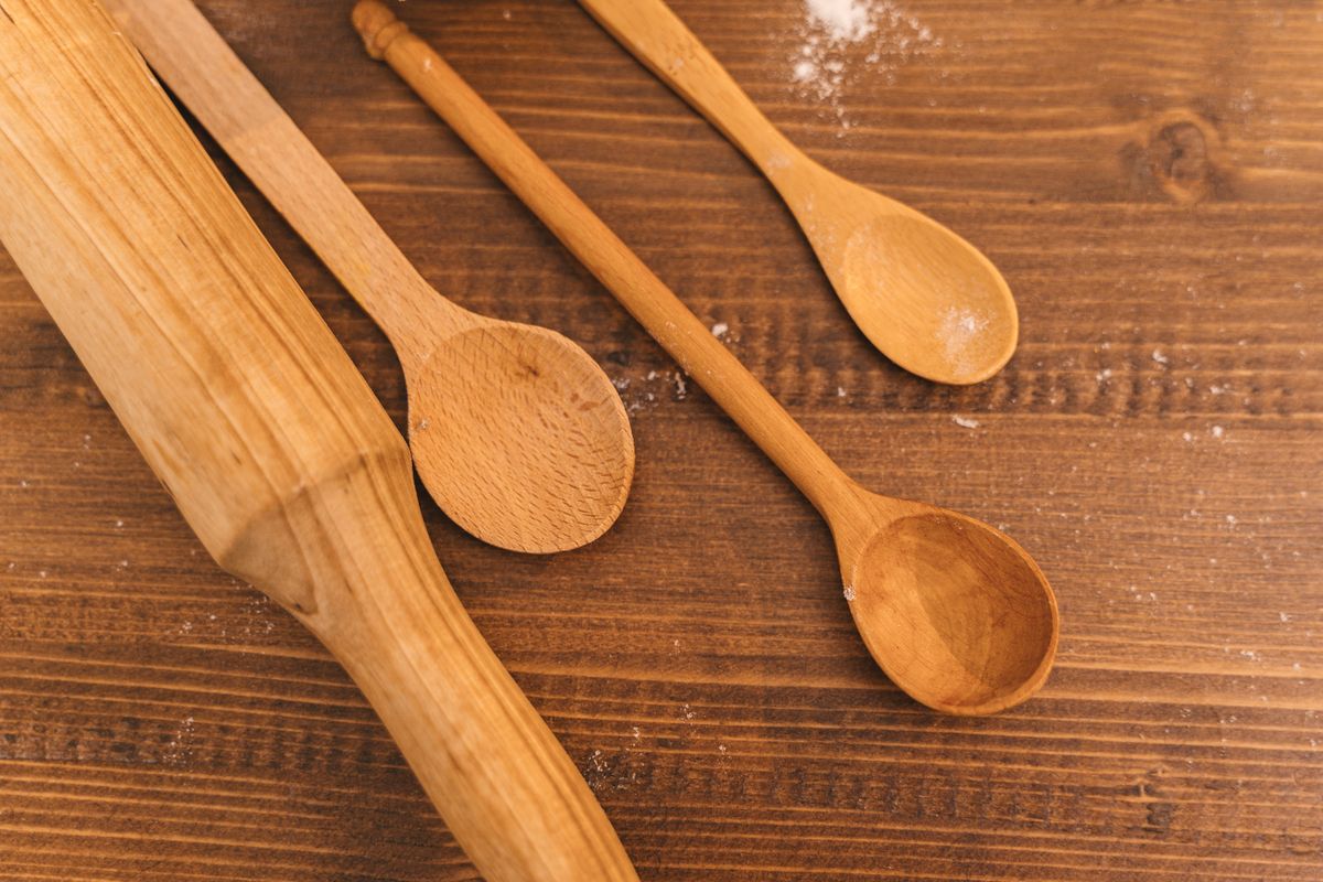 A collection of wooden kitchen utensils on a rustic wooden table, showcasing spoons and a rolling pin.