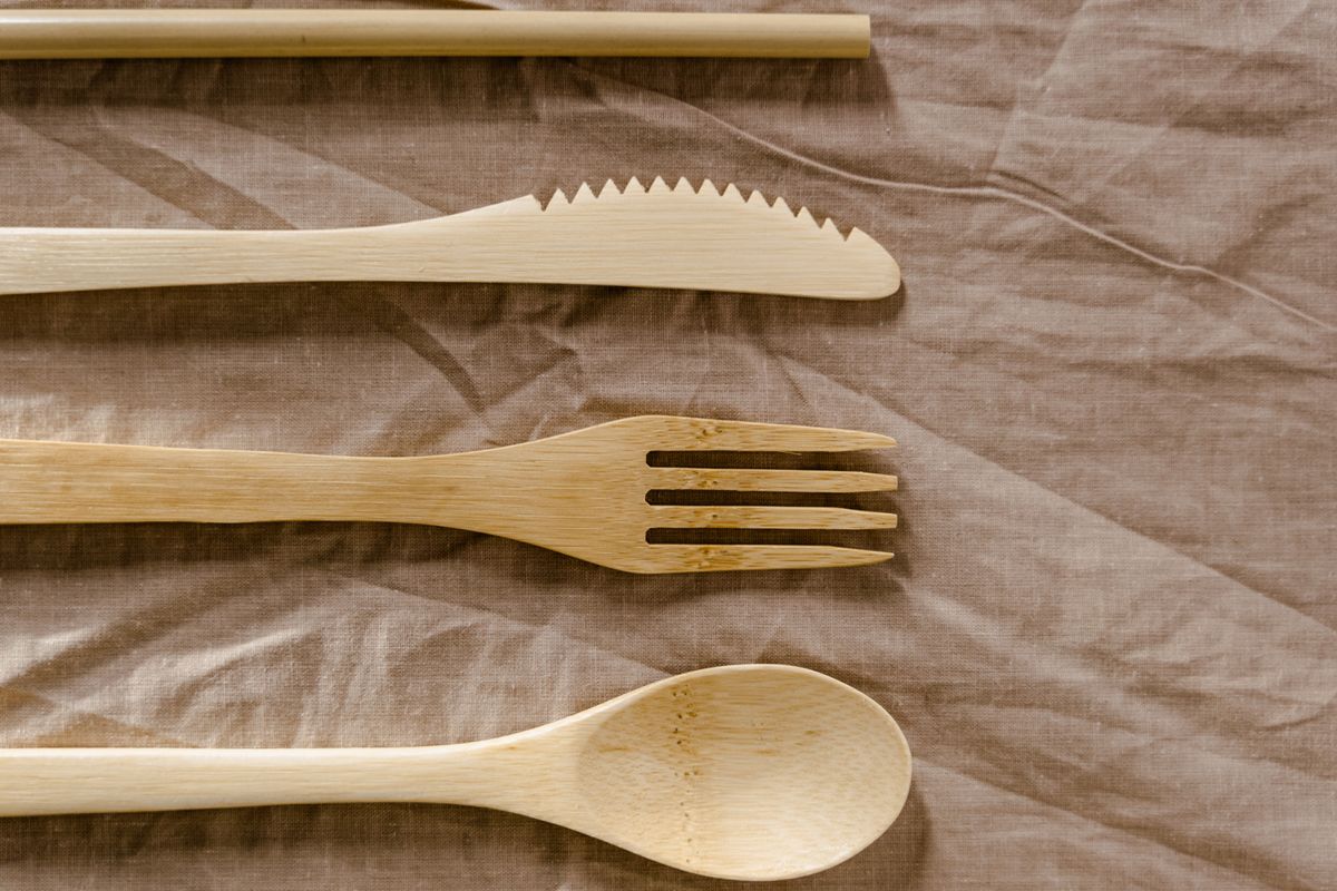 Top view of eco-friendly wooden utensils placed on textured textile, showcasing natural design.