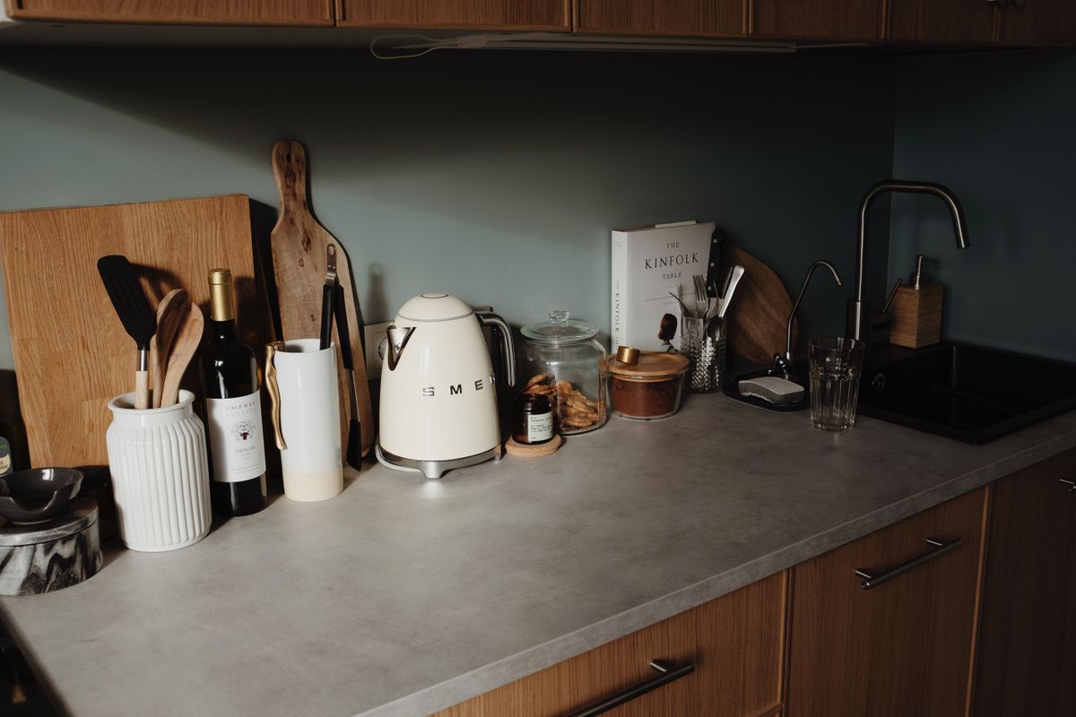 Composed utensils and appliance on gray stone counter of cozy kitchen in beam of soft sunlight