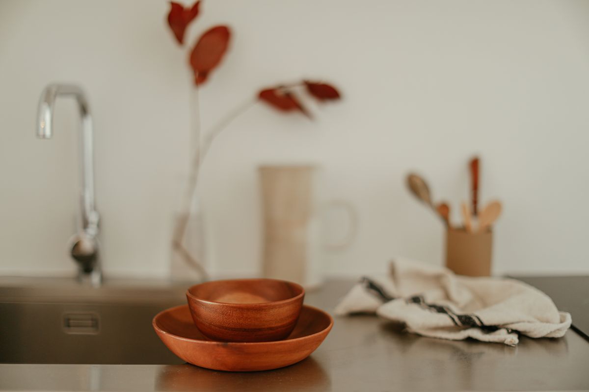 A serene, minimalist kitchen setup featuring wooden bowls and a stainless steel faucet.