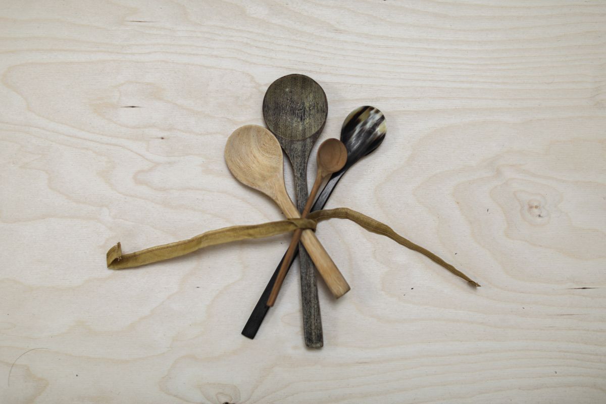 A set of rustic wooden kitchen utensils tied together with a string on a wooden table.
