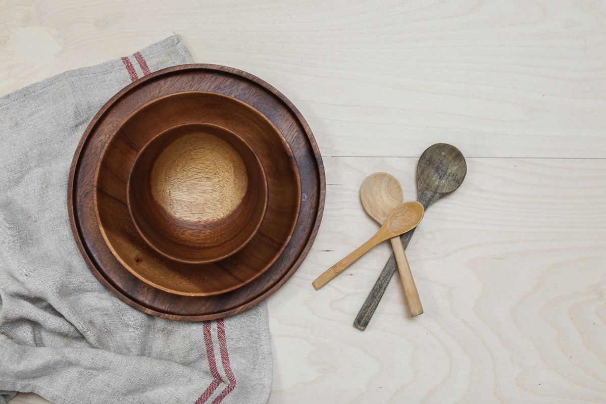 Close-up of rustic wooden bowls and spoons on a kitchen table with a linen cloth.