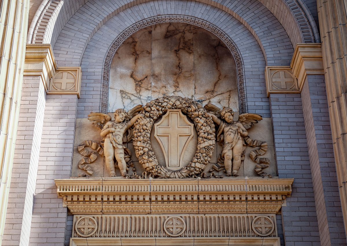 A detailed architectural relief featuring angels and a cross on a historic building facade.