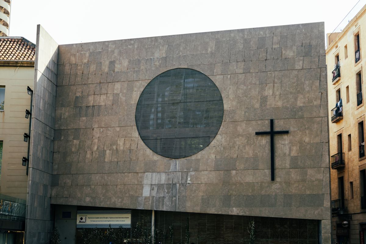 Contemporary church building facade in Barcelona featuring a cross and circular window.