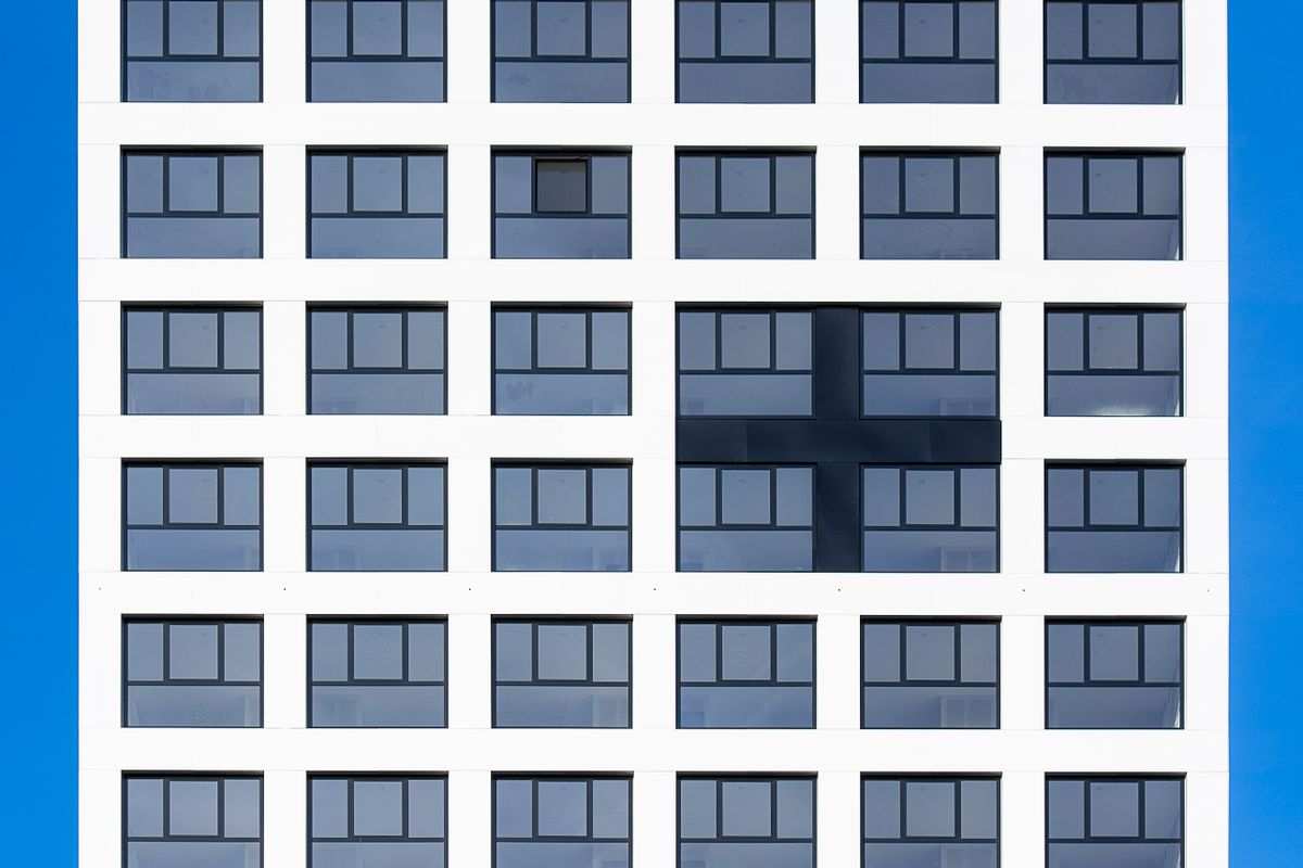 Symmetrical building facade with unique cross pattern, blue sky backdrop.
