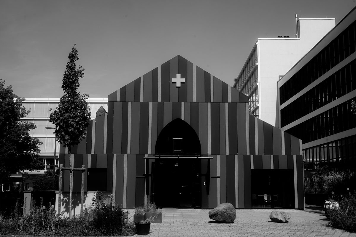 Black and white architectural photo of a modern building with striped facade and cross symbol.