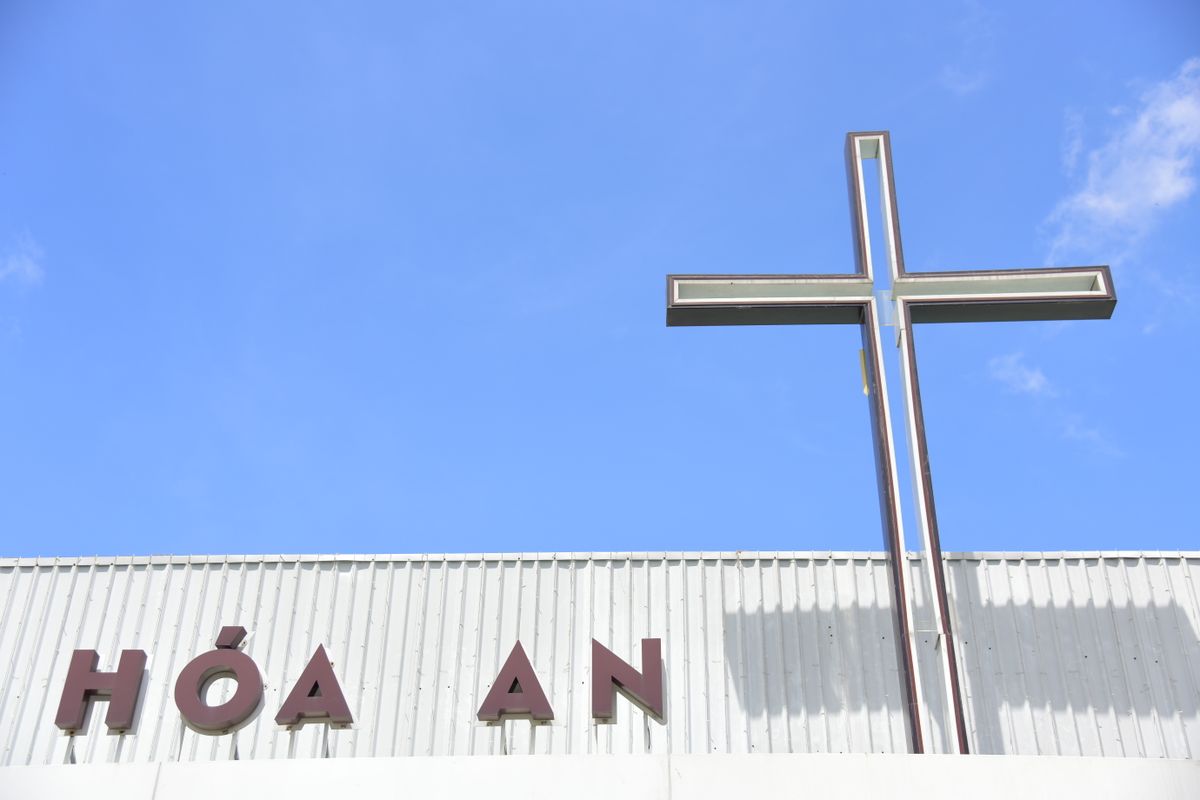 A church building with a prominent cross structure and clear blue sky background.