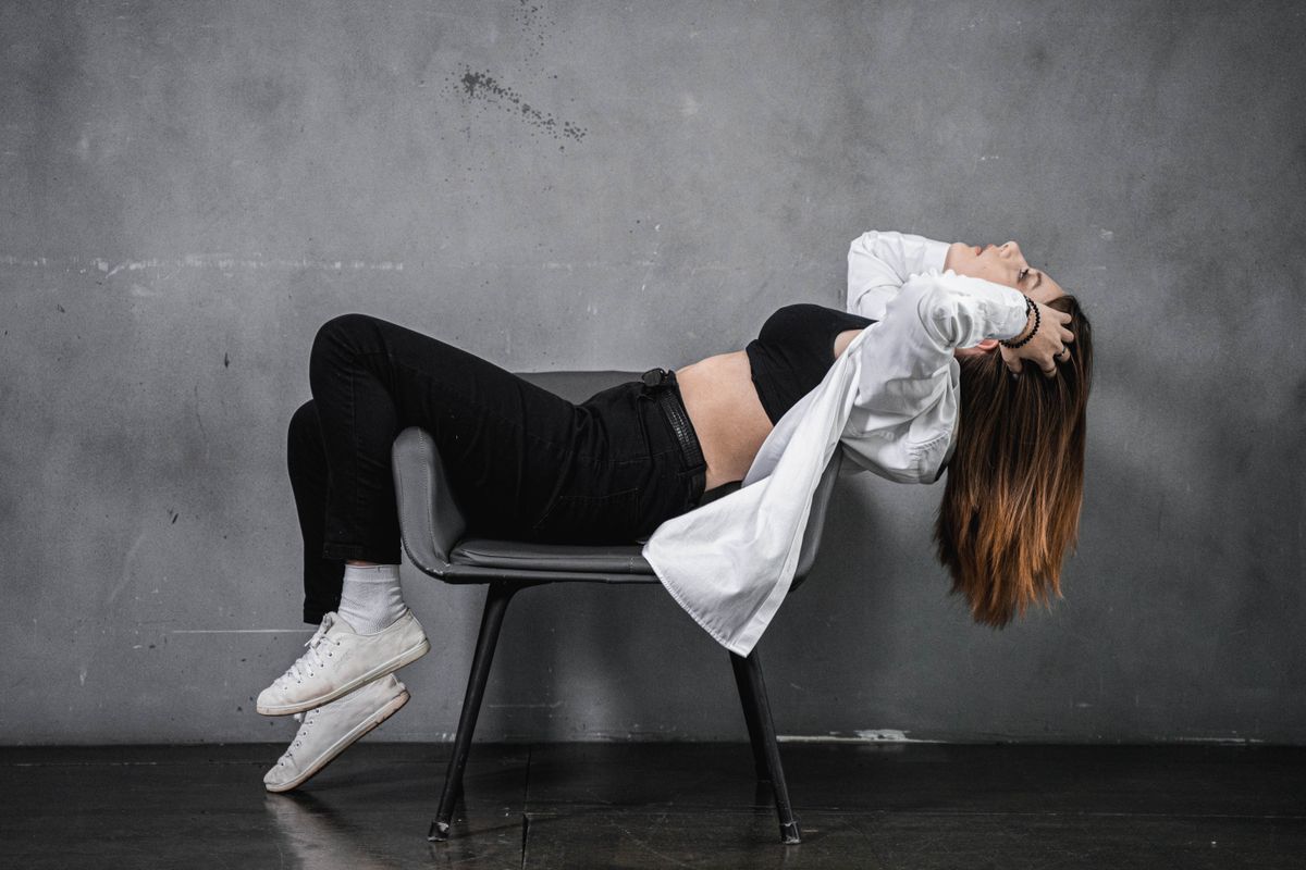 Fashionable woman posing dramatically on a chair, exuding style and confidence.