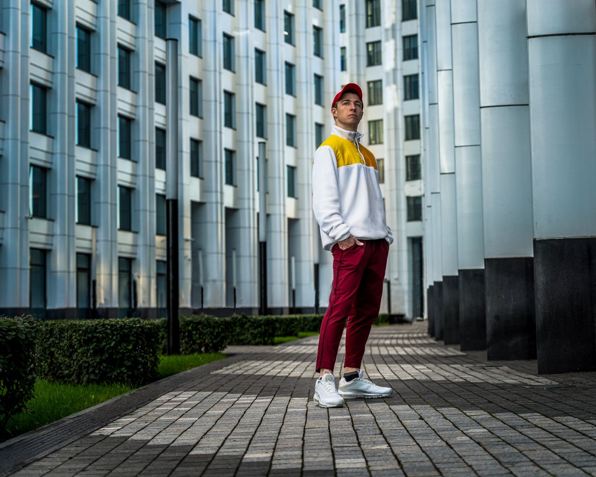 Fashionable man in streetwear style posing outdoors in Moscow, showcasing modern urban fashion.