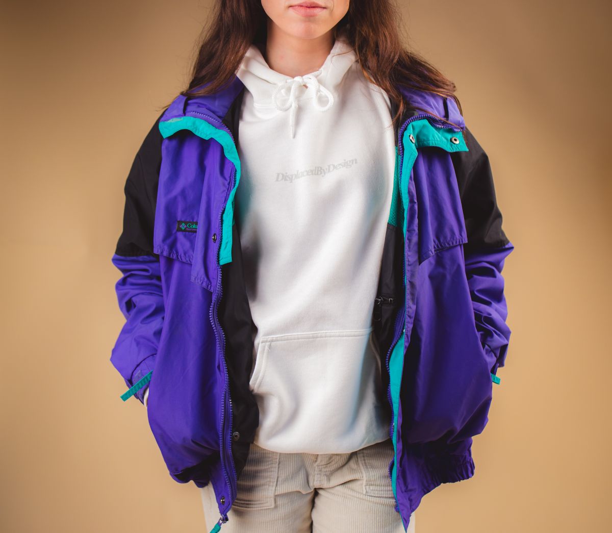 Fashionable young woman wearing a vibrant winter jacket and hoodie, showcasing modern streetwear style.