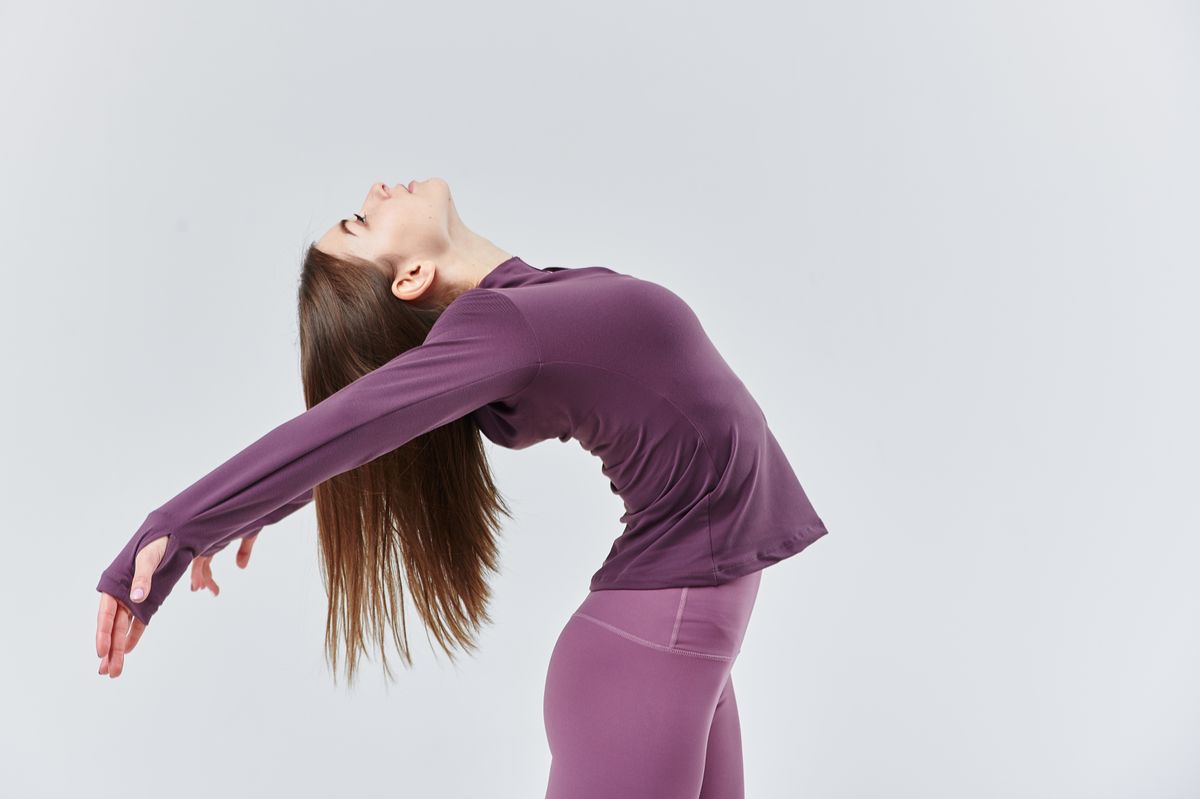 A young woman in a dynamic yoga pose wearing pink athletic wear, showcasing flexibility and balance.
