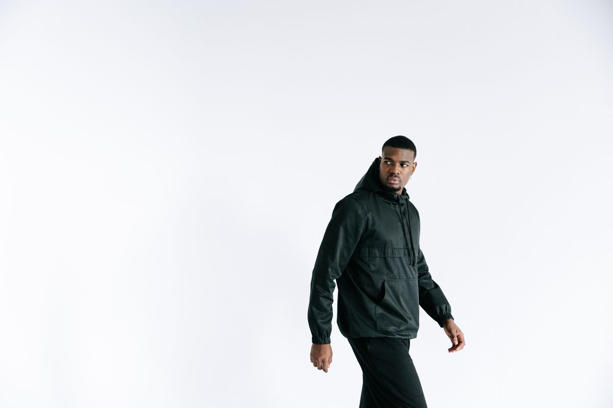 A fashion-forward African American man wearing a black jacket on a white background.