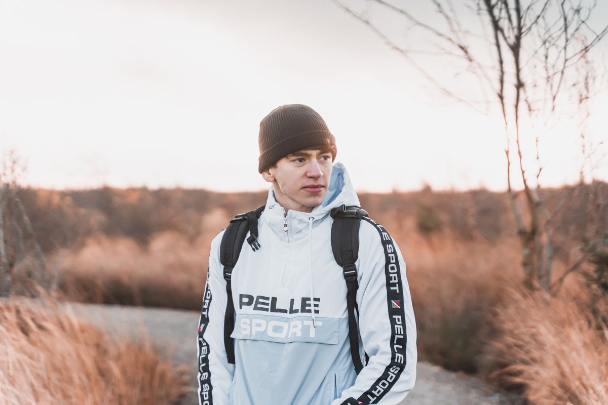 A young man wearing a jacket and beanie enjoying a walk outdoors in autumn.