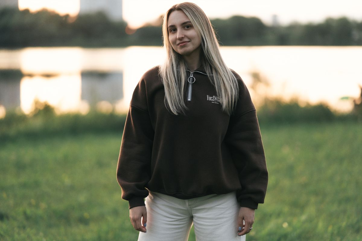 Young woman in casual outfit stands outdoors during sunset in Minsk, Belarus. Serene and natural setting.