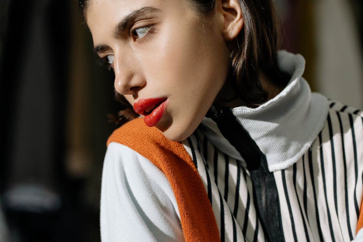 Stylish close-up portrait of an adult woman with striking red lips, wearing modern striped attire.