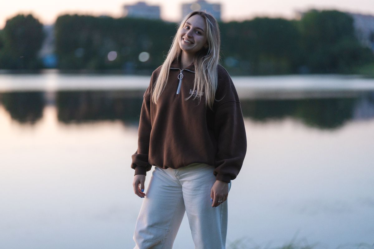 A woman enjoying a peaceful moment by the lakeside at dusk, wearing casual attire.