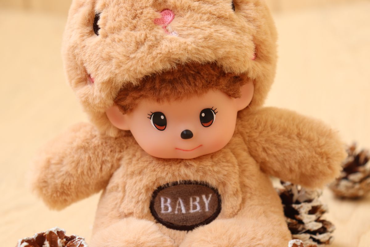Cute plush doll in fuzzy bear outfit with pine cones around. Perfect for children's gifts.