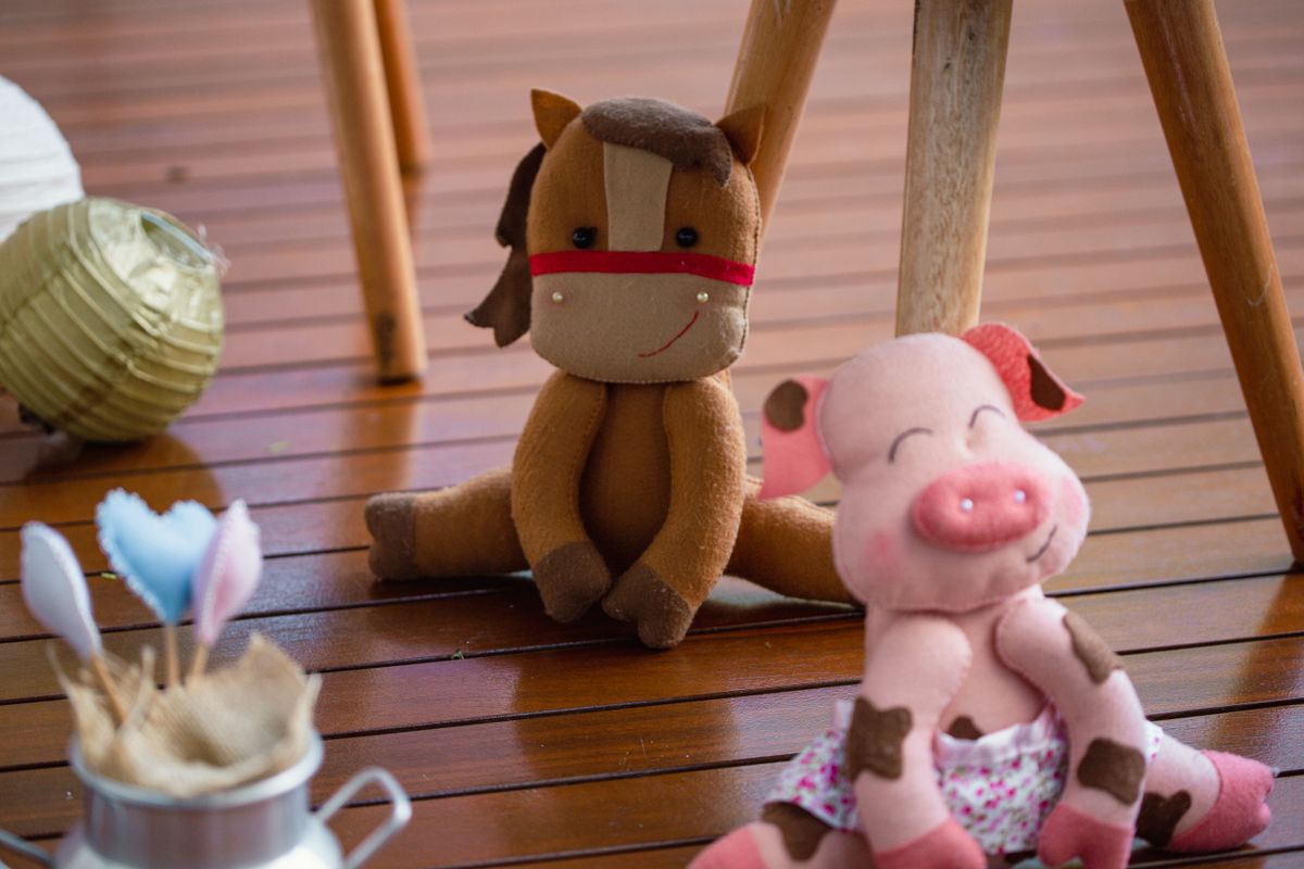 Adorable plush horse and pig toys on a wooden floor, evoking playful childhood memories.