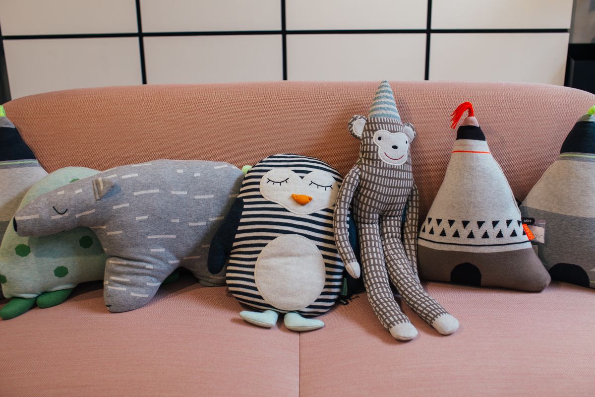 Collection of various soft toys placed in row on comfortable sofa in modern apartment