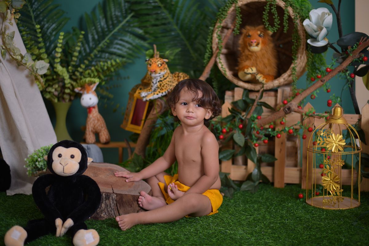 Adorable child in a jungle-themed setting with plush animals and vibrant decor.