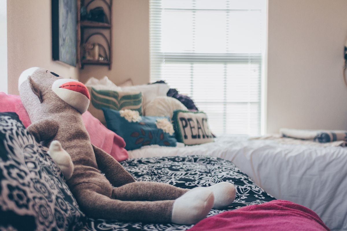 A cozy bedroom featuring a plush monkey toy and decorative pillows on a stylish bed.