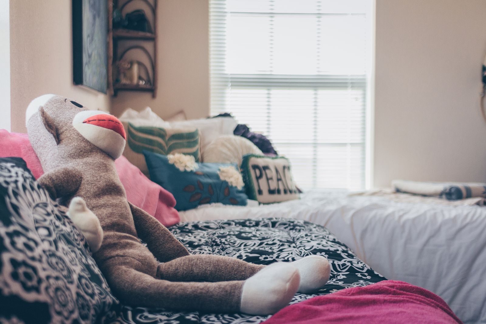 A cozy bedroom featuring a plush monkey toy and decorative pillows on a stylish bed.