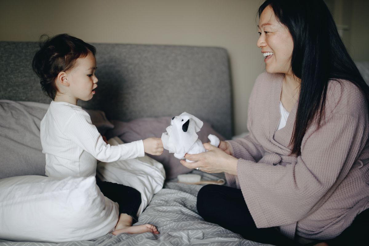 A mother and child bonding through play in a cozy bedroom setting.