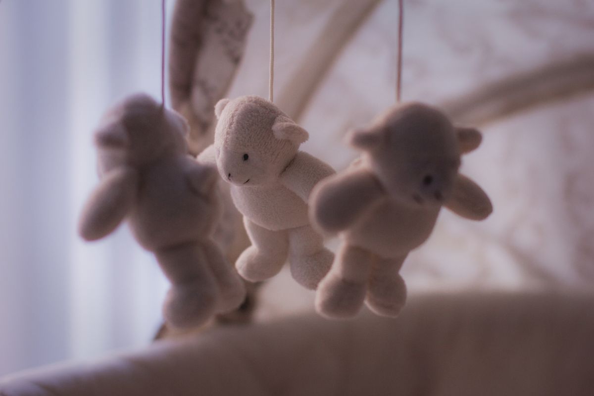 Adorable plush teddy bear mobile hanging over a baby crib, perfect for nursery decor.