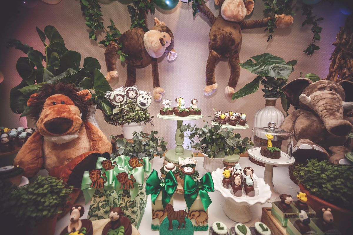 A captivating jungle safari themed dessert table with plush toys and greenery, perfect for children's celebrations.