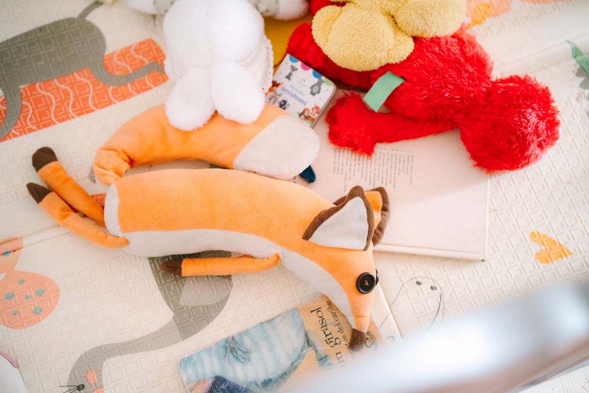 A collection of plush toys on a children's play mat featuring animal designs.