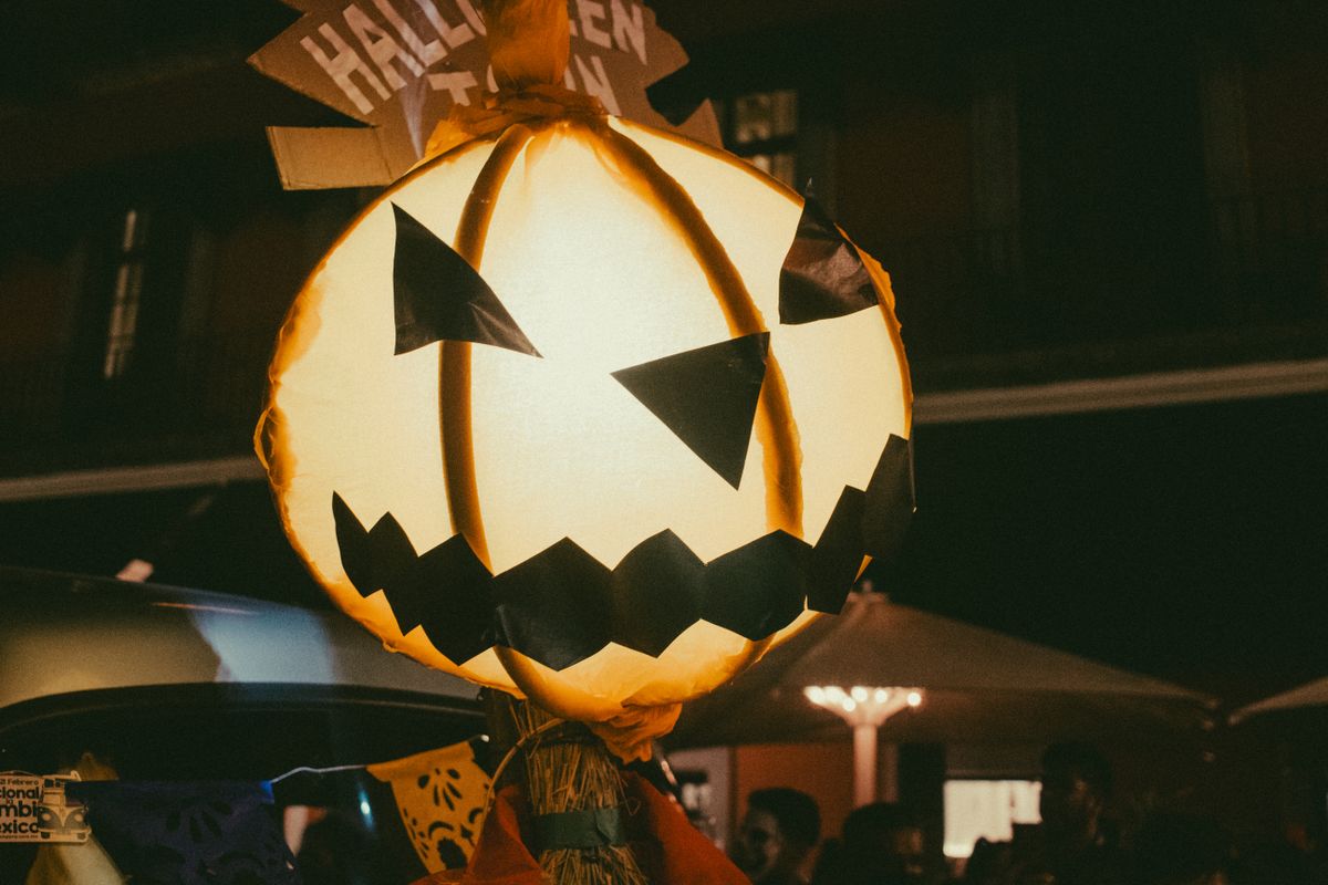 A glowing jack-o-lantern decoration lights up the night at an urban Halloween festival.