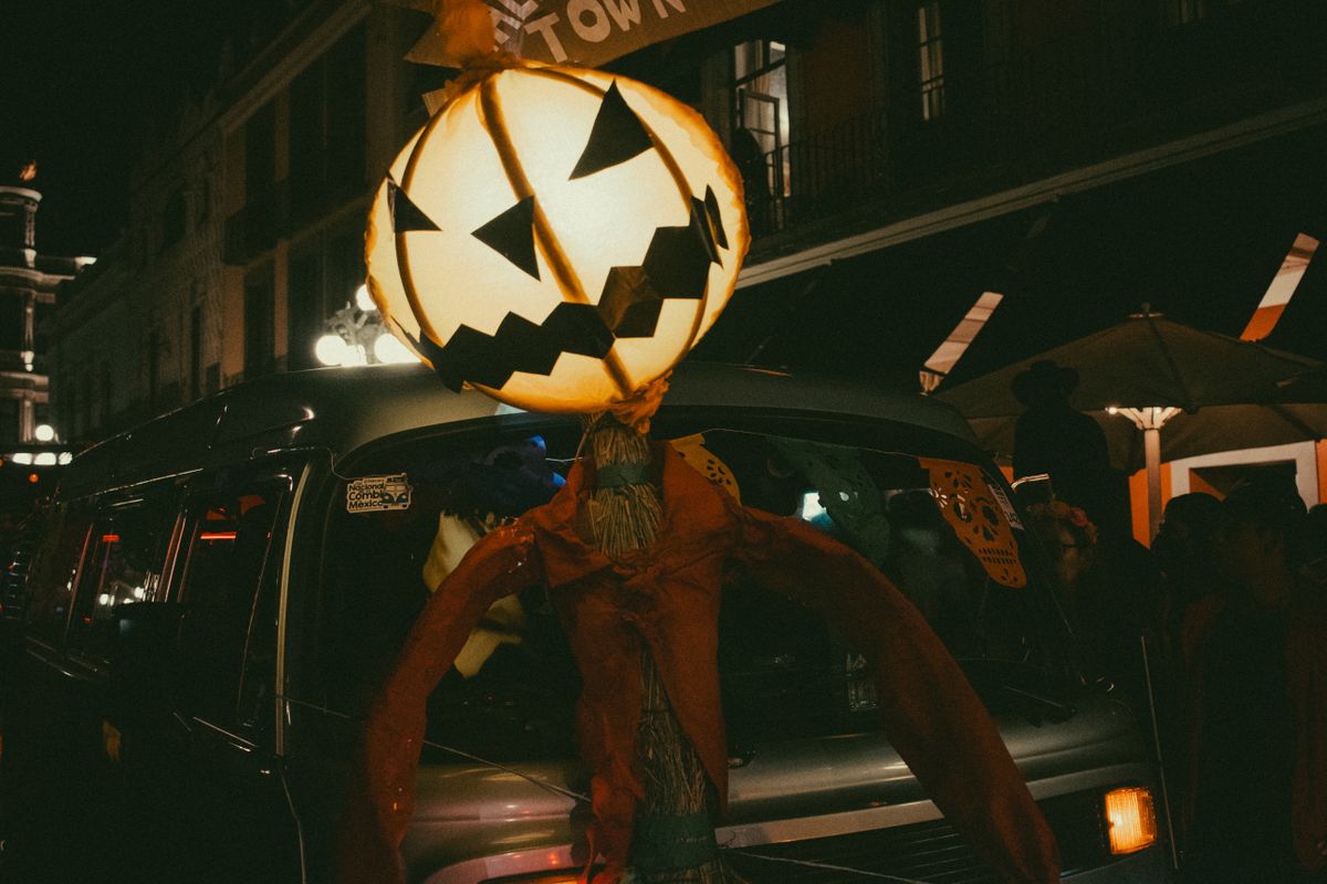 A giant pumpkin lantern decorates a street, creating a spooky Halloween ambiance at night.